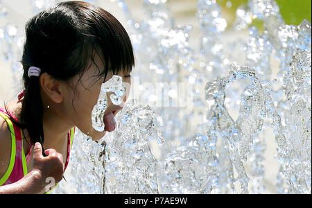 Germania Berlino. 04 Luglio, 2018. Una bambina viene aggiornata se stessa a temperature di 31 gradi Celsius in una città fontana nel quartiere governativo e gioca con le fontane d'acqua. Secondo i meteorologi, le temperature sono previste in aumento anche ulteriormente durante la settimana. Credito: Wolfgang Kumm/dpa/Alamy Live News Foto Stock