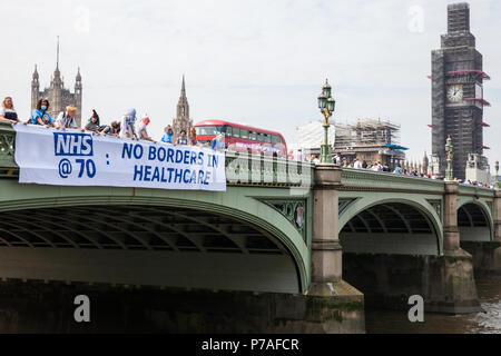 Londra, Regno Unito. 5 Luglio, 2018. Gli attivisti da Docs non poliziotti e il NHS Anti-Swindle caduta del team un banner da Westminster Bridge a leggere 'NHS@70: senza frontiere nel settore sanitario" in occasione del settantesimo compleanno del Servizio Sanitario Nazionale. Non Docs poliziotti è un gruppo composto da medici, infermieri, HIV attivisti, gli studenti, gli insegnanti e i laici che credono che la cura della salute è un diritto umano e si sono opposti alle politiche del governo che potrebbe rendere chiunque teme la visita di un medico per motivi di costo o di status di immigrazione. Credito: Mark Kerrison/Alamy Live News Foto Stock