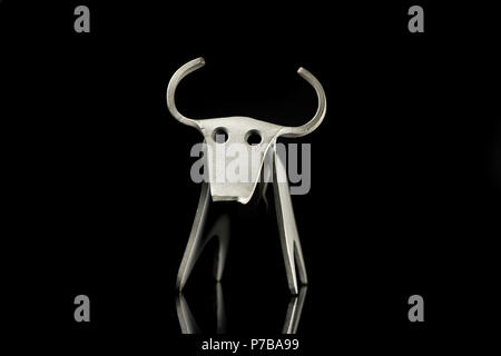 Abstract figurina di un toro fatto di piegato il foglio di alluminio, in piedi su un nero superficie riflettente Foto Stock