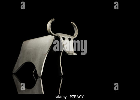 Abstract figurina di un toro fatto di piegato il foglio di alluminio, in piedi su un nero superficie riflettente Foto Stock