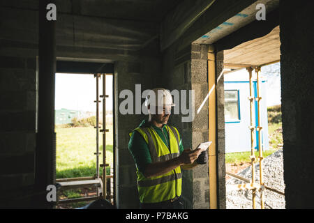Ingegnere con tavoletta digitale all'interno dell'edificio in costruzione Foto Stock