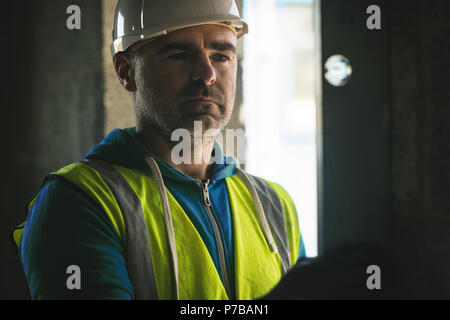 Ingegnere facendo un controllo di livello sulla parete al sito in costruzione Foto Stock