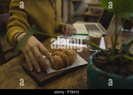 Giovane donna di prelevare un croissant Foto Stock