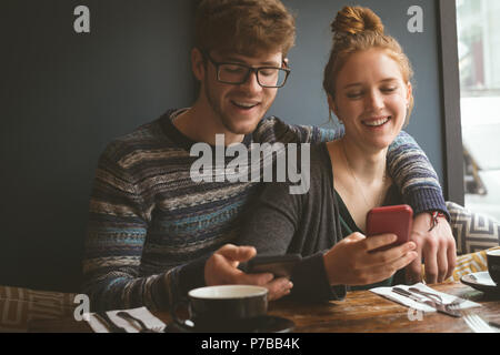 Paio utilizzando i telefoni cellulari al ristorante Foto Stock