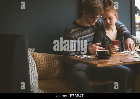 Paio utilizzando i telefoni cellulari in cafe Foto Stock