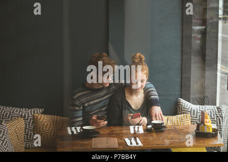 Paio utilizzando i telefoni cellulari in cafe Foto Stock