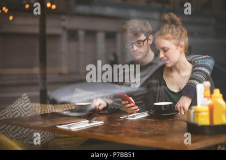 Paio utilizzando i telefoni cellulari in cafe Foto Stock