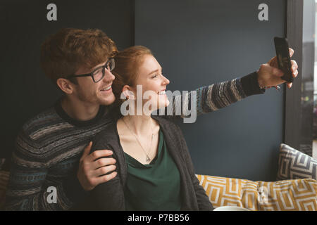 Giovane prendendo un selfie in cafe Foto Stock