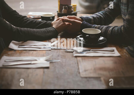 Giovane tenendo le mani nel cafe Foto Stock