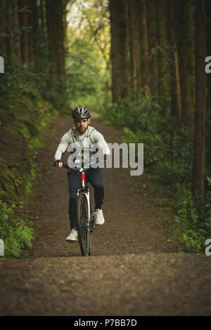 Ciclista Bicicletta Equitazione attraverso la lussureggiante foresta Foto Stock