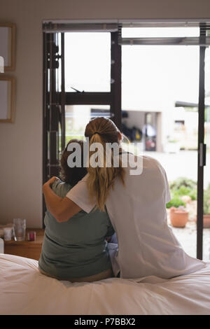 Fisioterapista abbracciando il senior donna a casa Foto Stock