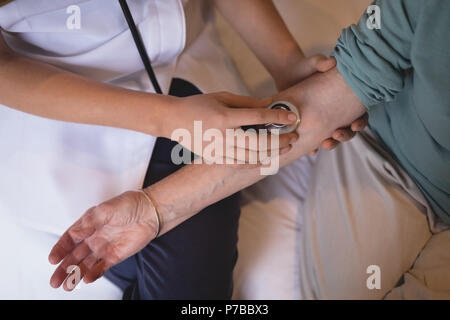 Fisioterapista esaminando senior donna con uno stetoscopio Foto Stock