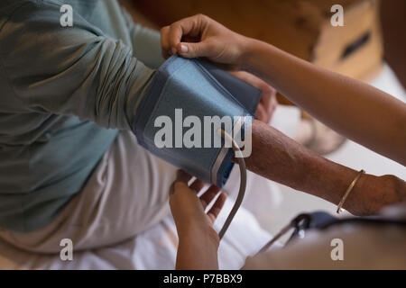 Fisioterapista controllando la pressione del sangue di donna senior Foto Stock