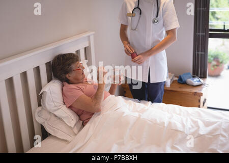 Fisioterapista dando medicina donna senior Foto Stock