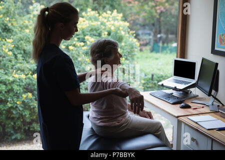 Fisioterapista dando una mano al massaggio donna senior Foto Stock