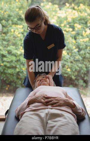 Fisioterapista dando un massaggio della testa di donna senior Foto Stock