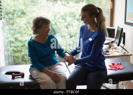 Fisioterapista dando una mano al massaggio donna senior Foto Stock