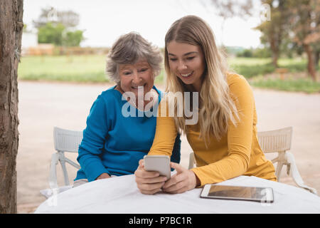 La nipote e nonna utilizzando uno smartphone Foto Stock