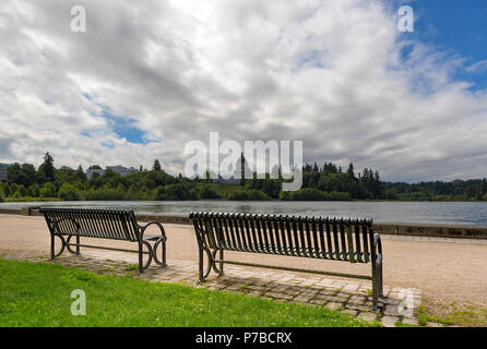 Una panchina nel parco lungo la panoramica Lago Capitol in Olympia nello Stato di Washington in un giorno nuvoloso Foto Stock