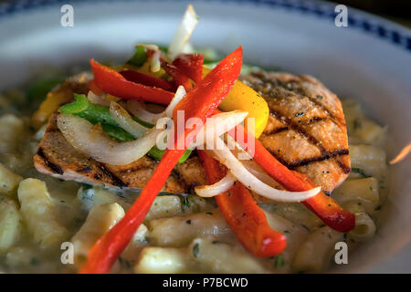 Grigliata di Wild Alaskan Salmone con cipolle peperoni più cremoso alfredo penne pasta piatto cena closeup Foto Stock