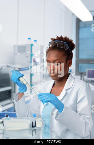 African-scienziato americano o studente laureato in camice protettivo e di opere di usura in laboratorio modernl Foto Stock