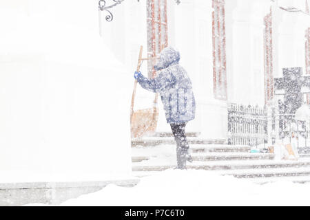 La donna la pulizia della neve con pala in giorno d'inverno. Tempesta di neve Foto Stock