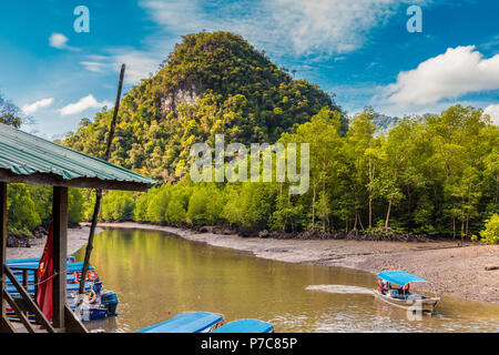 Una barca di legno e dock ormeggiate barche a motore nella parte anteriore di una bella collina calcarea presso il molo Kilim, situato a nord-est bordo di Langkawi. Foto Stock