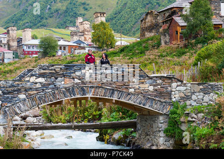 Georgian giovane da un gruppo folcloristico su un ponte di pietra di fronte Ushguli villaggio, per il solo uso editoriale, Ushguli, regione di Svaneti, Georgia Foto Stock