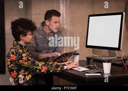 Maschio e femmina di dirigenti che lavorano su computer a scrivania Foto Stock