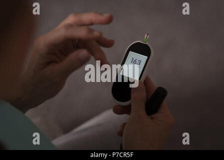 Senior donna controllando la pressione del sangue su un monitor Foto Stock