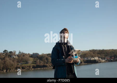 Escursionista maschio drone operativo vicino al lago Foto Stock