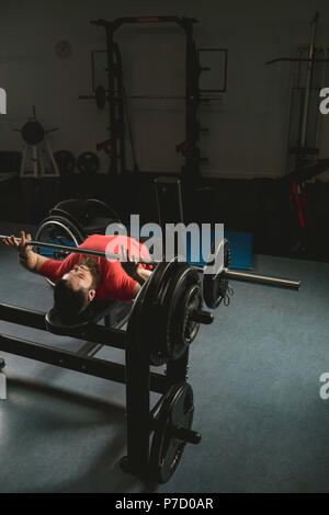 Uomo disabile facendo barbell bench premendo durante l'esercizio Foto Stock