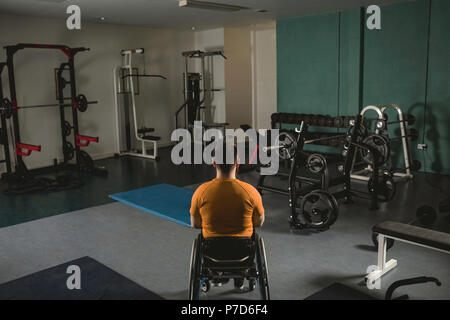 Uomo disabile rilassante sulla sedia a rotelle in palestra Foto Stock