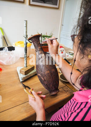 Donna di incollaggio a forma di minuscoli cloisonne fili in un vaso di rame creando un complicato modello costruito per un smalto cloisonne vase, Pechino, Cina Foto Stock