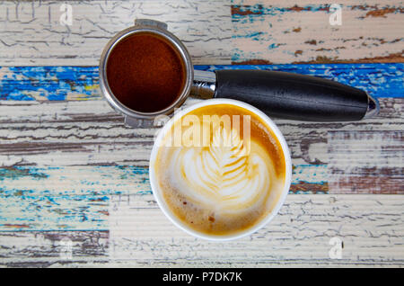 Una tazza di latte, cappuccino o caffè espresso con latte mettere su un tavolo in legno scuro con chicchi di caffè tostati Foto Stock