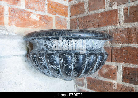 Antica acqua santa font o acquasantiera, pietra nera fatta nave, dettaglio. Cattedrale di Gniezno, Polonia Foto Stock