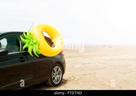Un anello di nuotare in forma di ananas su una vettura, sulla sabbia di una spiaggia, con il mare in background, con qualche spazio vuoto sulla destra Foto Stock