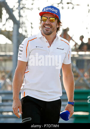 Il pilota della McLaren Fernando Alonso onde ai fan come egli cammina sulla pista, paddock durante il giorno del 2018 British Grand Prix sul circuito di Silverstone, Towcester. Foto Stock