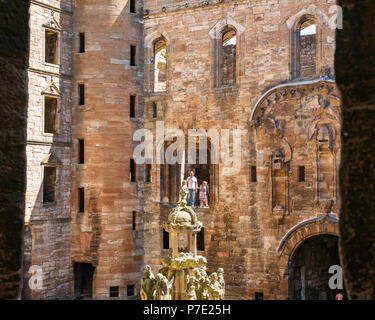 Rovinato interno cortile centrale con la famiglia in piedi in rovina il telaio del finestrino, Linlithgow Palace, West Lothian, Scozia, Regno Unito Foto Stock