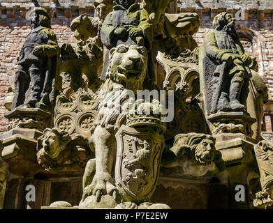 Dettaglio di indossato scolpiti leone rampante e figure, ornata fontana di pietra nel cortile centrale, Linlithgow Palace, West Lothian, Scozia, Regno Unito Foto Stock