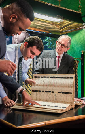 Sarti e il cliente sta guardando a mano swatch libro nel tradizionale negozio di sartoria, ritratto Foto Stock