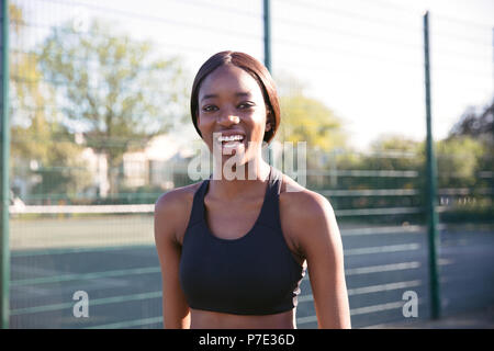 Giovane donna sorridente in campo sportivo Foto Stock