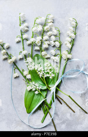 Il giglio della valle dei fiori recisi, foglie e nastro Foto Stock