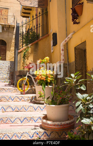 Italia Sicilia Agrigento città vecchia viuzze ripide scene dipinte di pietra gradini scale piantatrici piante cactus cactus case balconi drainpipe Foto Stock