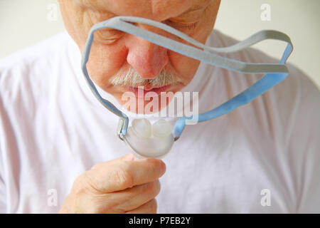 Vista dettagliata del senior l'uomo con il copricapo porzione di una pressione positiva continua delle vie respiratorie macchina per apnea nel sonno Foto Stock