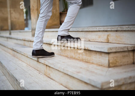 Sezione bassa di un uomo a camminare su per le scale Foto Stock
