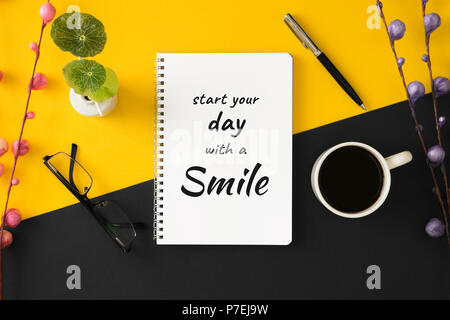 Notebook con motivazionali e saggezza ispiratrice preventivo su giallo e sfondo nero. Iniziate la vostra giornata con un sorriso. Foto Stock