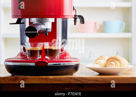 Due tazze di espresso sulla macchina espresso con un croissant Foto Stock