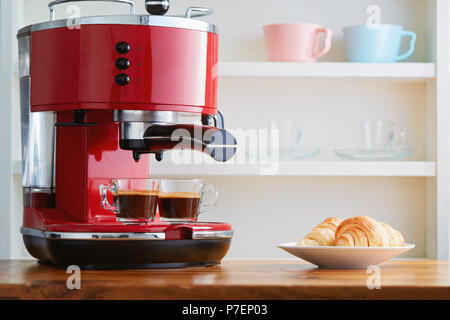 Due tazze di espresso sulla macchina espresso con un croissant Foto Stock