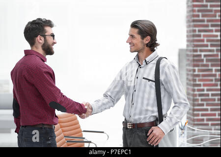 Stretta di mano di due dipendenti in piedi in ufficio Foto Stock